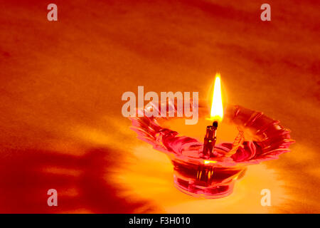 Bildende Kunst; einzelne einer Diya Kunststoff Öl Lampe Lichtquelle als Flamme auf orangem Hintergrund Stockfoto