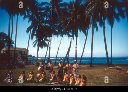 Touristen besuchen eine Luau auf Hawaii in den 1950er Jahren mit Unterhaltung von Hawaiianer. Hula-Tänzer und Hawaiianer Musizieren Stockfoto