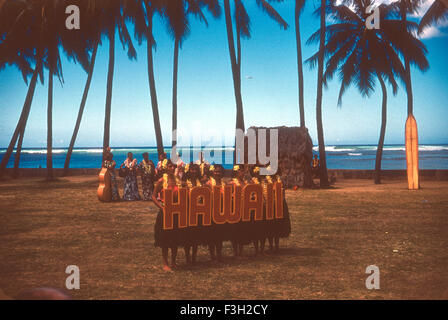 Touristen besuchen eine Luau auf Hawaii in den 1950er Jahren mit Unterhaltung von Hawaiianer. Hula-Tänzer mit Hawaii-Schild, während Musiker traditionelle hawaiianischen Musik spielen Stockfoto