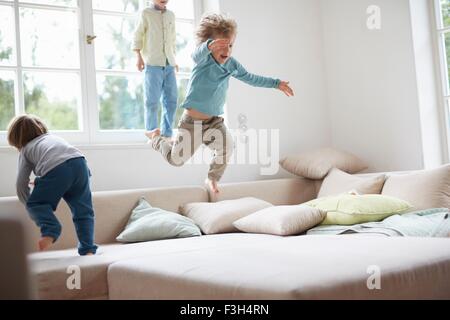 Drei junge Burschen springen auf sofa Stockfoto