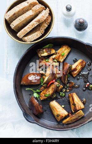 Stillleben mit gebratenen Auberginen und Kräutern in der Pfanne Stockfoto