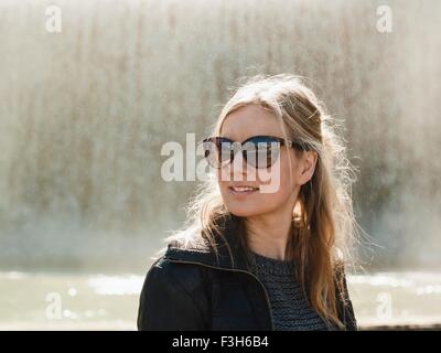 Porträt von Mitte Erwachsene Frau mit Sonnenbrille vor Brunnen auf dem Montjuic Hügel, Barcelona, Spanien Stockfoto