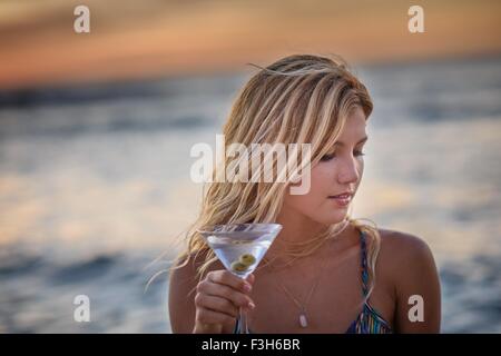 Junge Frau am Strand bei Sonnenuntergang cocktail trinken Stockfoto