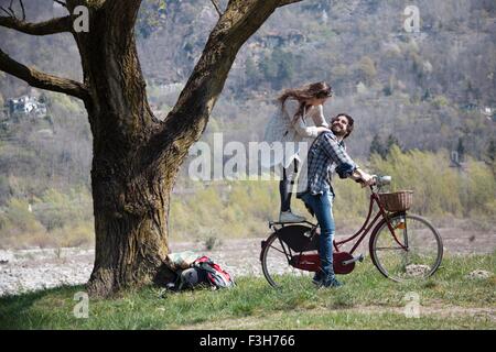 Junge Frau auf dem Fahrrad hinter Freund Stockfoto