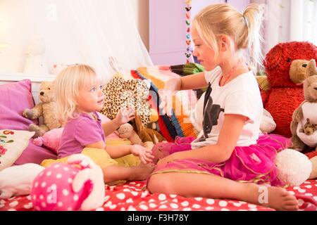 Mädchen und Kleinkind Schwester Hände Spiel auf Bett Stockfoto