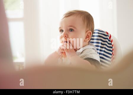 Baby Boy Fütterung selbst in Baby-Stuhl Stockfoto