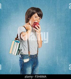 Sommersprossige junge tragen Zahnspangen, tragen Bündel von Büchern über die Schulter, Blick in die Kamera, Apfel beißen Stockfoto