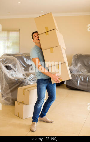 junger Mann mit einem Stapel Kartons bei der Umstellung auf neues Haus Stockfoto