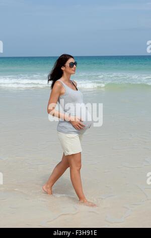Schwanger Mitte Erwachsene Frau spazieren am Strand Stockfoto