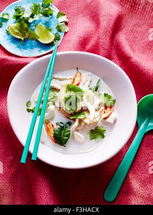 Draufsicht der Tom Kha Gai in Schüssel mit Stäbchen und Suppenlöffel Stockfoto