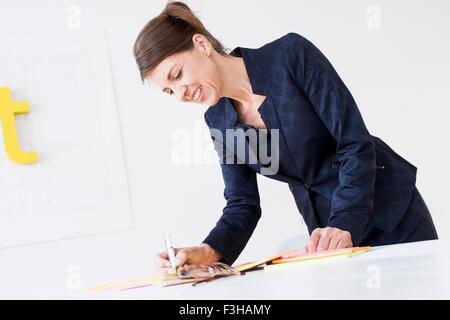 Reife Frau tragen Kleidung Geschäftsschreiben auf Papierkram, blickte lächelnd Stockfoto