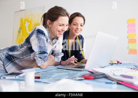 Reife Frauen am Schreibtisch ruht auf Ellbogen mit Laptop lächelnd Stockfoto