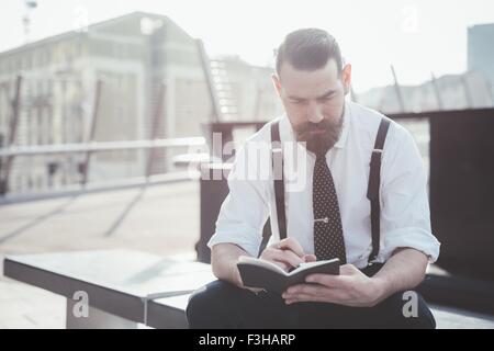 Stilvolle Geschäftsmann Tagebuch-Notizen vom Smartphone auf Stadt Sitz Stockfoto