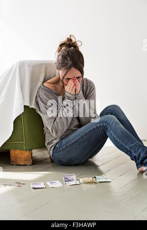 Reife Frau sitzen am Boden im Haus, distressed Geldzählen, Ausdruck Stockfoto