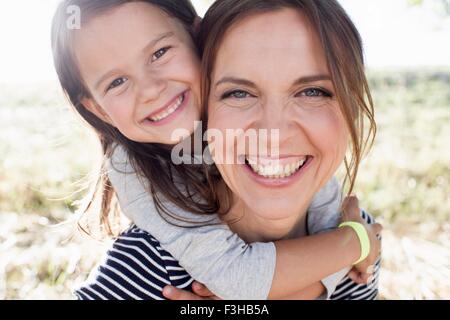 Porträt von Reife Frau und Tochter Piggy back im park Stockfoto