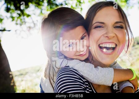 Porträt von Reife Frau und Tochter Schweinchen zurück im sonnigen park Stockfoto