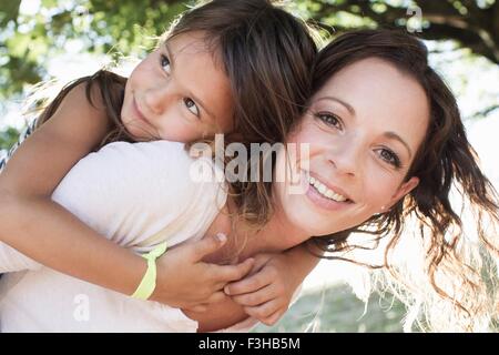 Porträt von Reife Frau und Tochter Piggy back im park Stockfoto