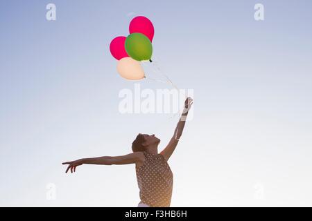 Niedrigen Winkel Blick auf Reife Frau Haufen Luftballons gegen Blues Himmel hochhalten Stockfoto