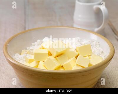 Stillleben mit Backzutaten. Würfel Butter und Mehl mischen Bogen Stockfoto