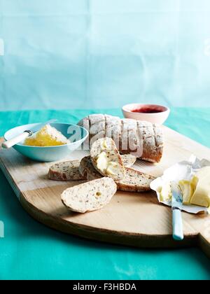 Schneidbrett mit frischem unkneaded Brot mit Honig, Butter und Marmelade Stockfoto