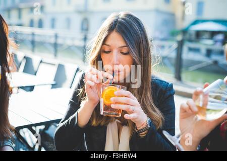 Junge Frau und Freunde tranken Cocktails im Waterfront café Stockfoto