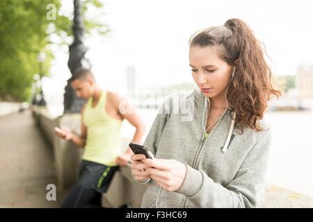 Zwei Läufer SMS auf Smartphone im riverside Stockfoto