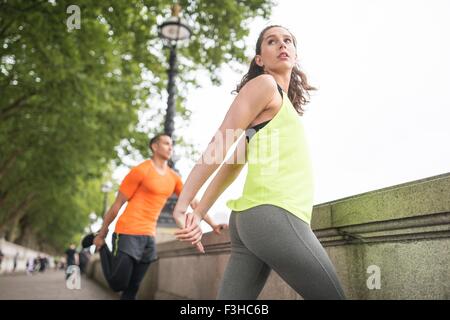 Junge männliche und weibliche Läufer Aufwärmen am Ufer Stockfoto