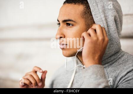 Männliche Läufer tragen Grey hoody Kopfhörer Musik hören Stockfoto