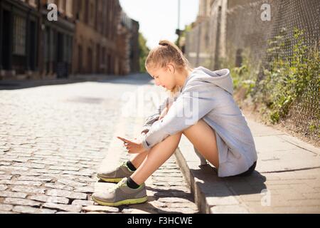 Läufer mit Smartphone auf Bürgersteig, Wapping, London Stockfoto