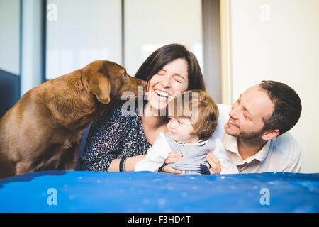 Mitte erwachsenes paar mit Kleinkind Tochter und Hund lachen Stockfoto