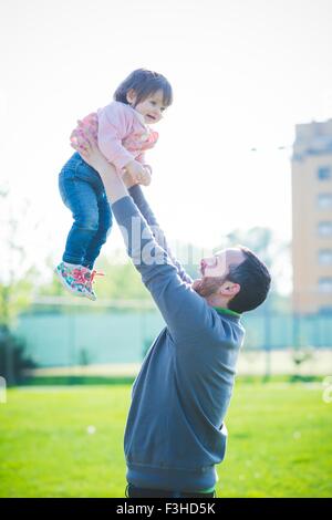 Mitte erwachsener Mann hob Kleinkind Tochter im park Stockfoto