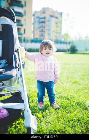 Weiblichen Kleinkind festhalten an Kinderwagen im park Stockfoto