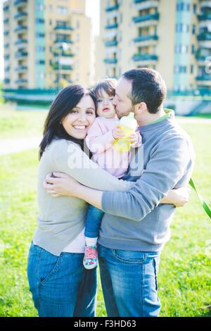 Porträt von Mitte erwachsenes paar küssen Kleinkind Tochter im park Stockfoto