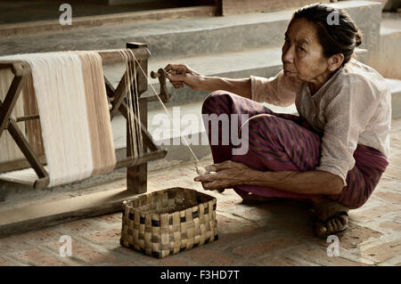 Alten burmesischen Frau hockend mit einem Spinnrad in Bagan, Mandalay Region, Myanmar Stockfoto