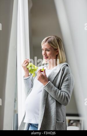 Volle Amtszeit Schwangerschaft junge Frau essen Trauben Stockfoto