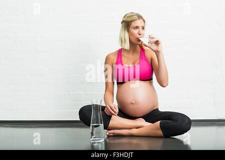 Volle Amtszeit Schwangerschaft junge Frau Trinkwasser während Yoga üben Stockfoto