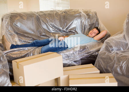 müde Menschen schlafen auf der Couch im neuen Zuhause mit Kartons rund um Stockfoto