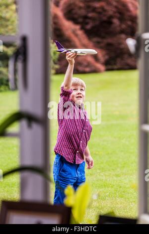 Junge spielt im Garten mit Spielzeugflugzeug Stockfoto