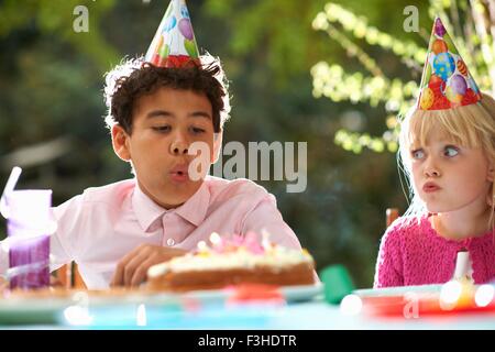 Boy bläst Kerzen auf Geburtstagskuchen auf Garten Geburtstagsparty Stockfoto