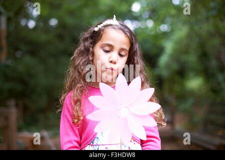 Mädchen bläst Windrad Blume im Garten Geburtstagsfeier Stockfoto