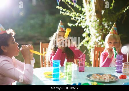 Jungen und Mädchen bläst Partei Hörner auf Garten Geburtstagsparty Stockfoto