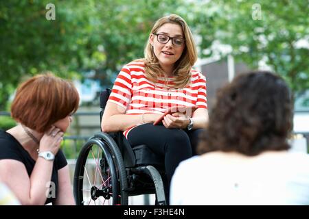 Studentin im Rollstuhl unterhielt sich mit Freunden auf College-campus Stockfoto