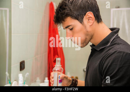 Kopf und Schultern enger bis der attraktive junger Mann mit dunklen Haaren spülen mit Mundwasser im Bad als Teil des Morgens Groomi Stockfoto