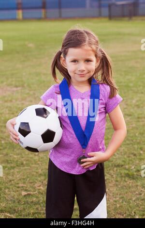 Porträt von Mädchen-Football-Spieler mit Medaille auf Praxis-Stellplatz Stockfoto