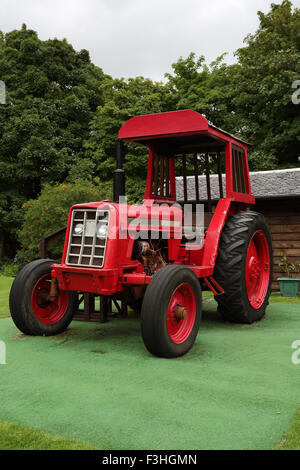 Eine alte rote Traktor geparkt auf dem grünen Rasen Stockfoto