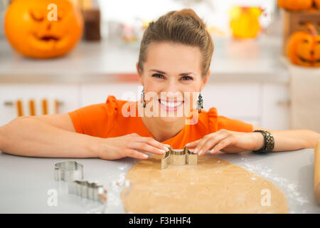 Glückliche junge Hausfrau, Halloween Kekse mit Gebäck Cutter ausschneiden, aus gerollten Teig in Küche dekoriert für Horror-party Stockfoto