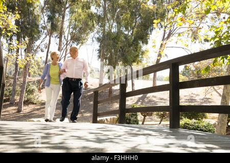 Älteres Paar gehen Arm in Arm über Fußgängerbrücke Stockfoto