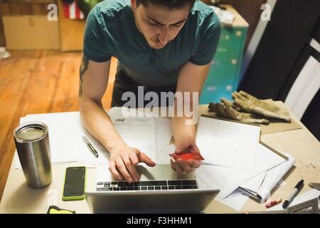 Erhöhte Ansicht des jungen Mannes mit Kreditkarte und Laptop, Online-Kauf zu tätigen Stockfoto