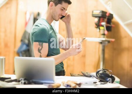 Seitenansicht der junge Mann am Telefon Kreditkarte lächelnd betrachtet sprechen Stockfoto