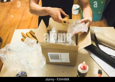 Erhöhte Ansicht der jungen mans Hände mit Luftpolsterfolie ein Paket Lieferung vorbereiten Stockfoto